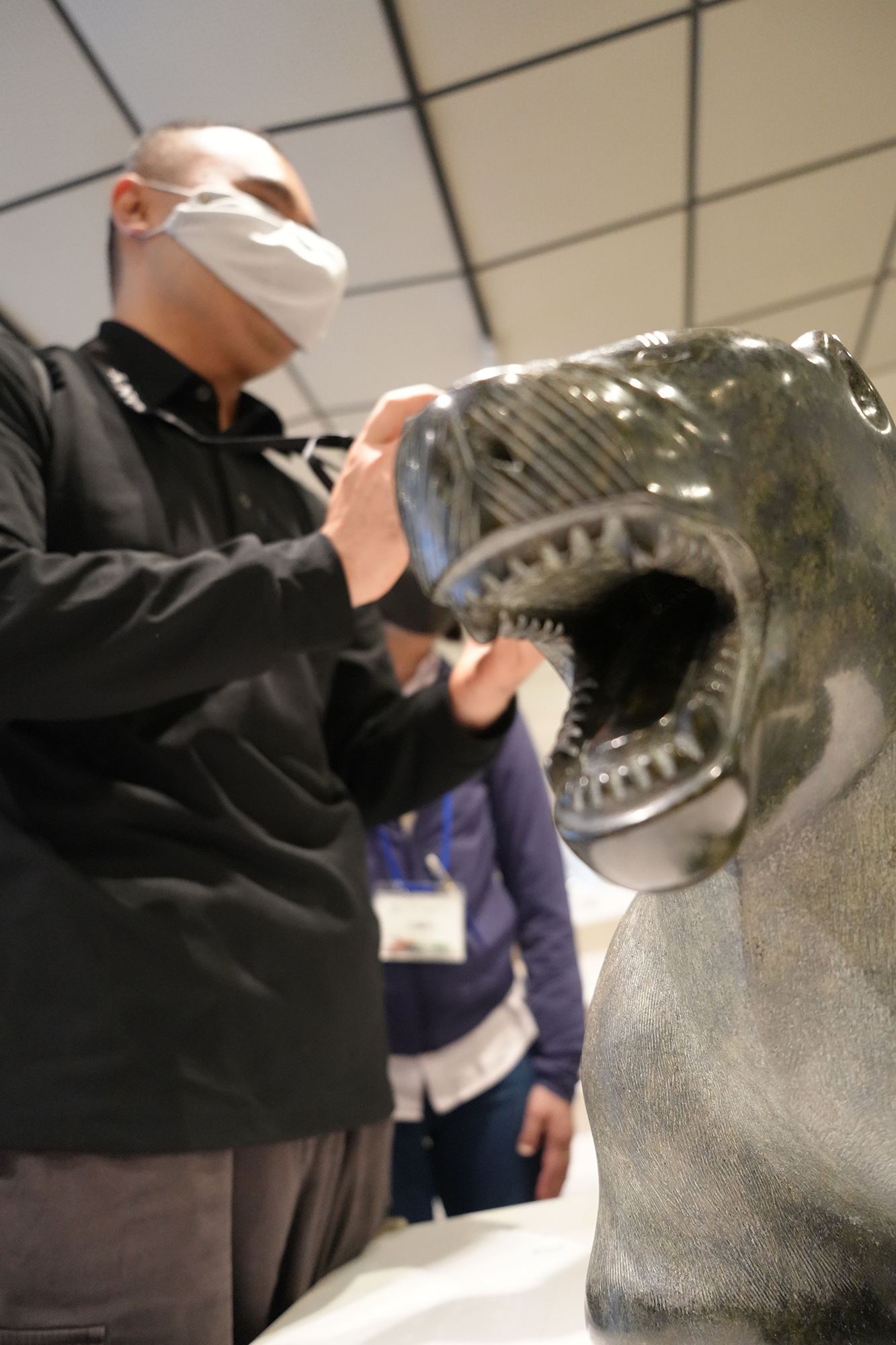 黒い石で作られたホッキョクグマの像に触れ、大きく開いた口や顔の形を確かめる濱崎さん。後ろにはガイドさんが立っている。