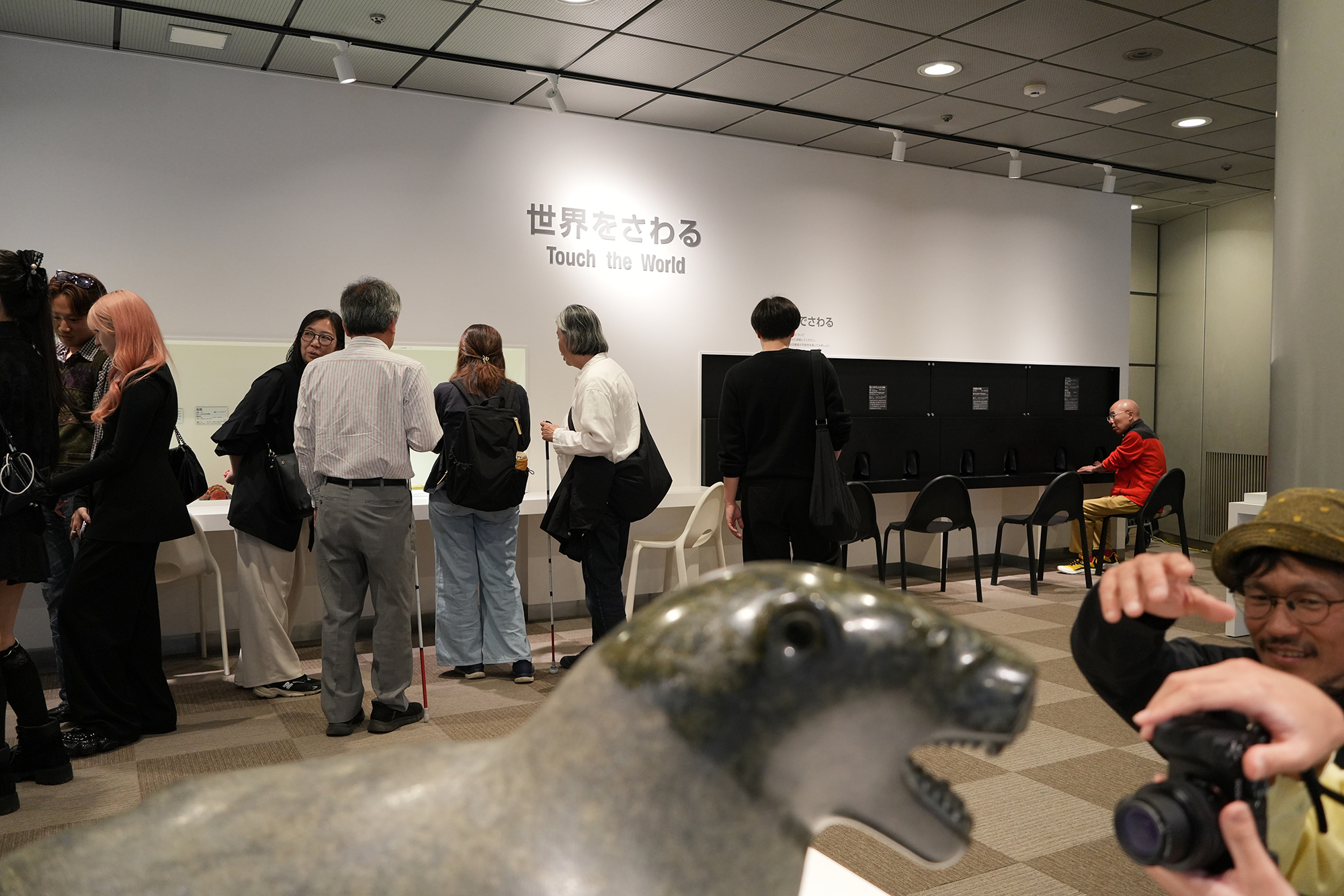 展示室内の様子を撮影した写真。手前にはホッキョクグマの像、奥には展示を見学する参加者や広瀬先生の姿が写っている。