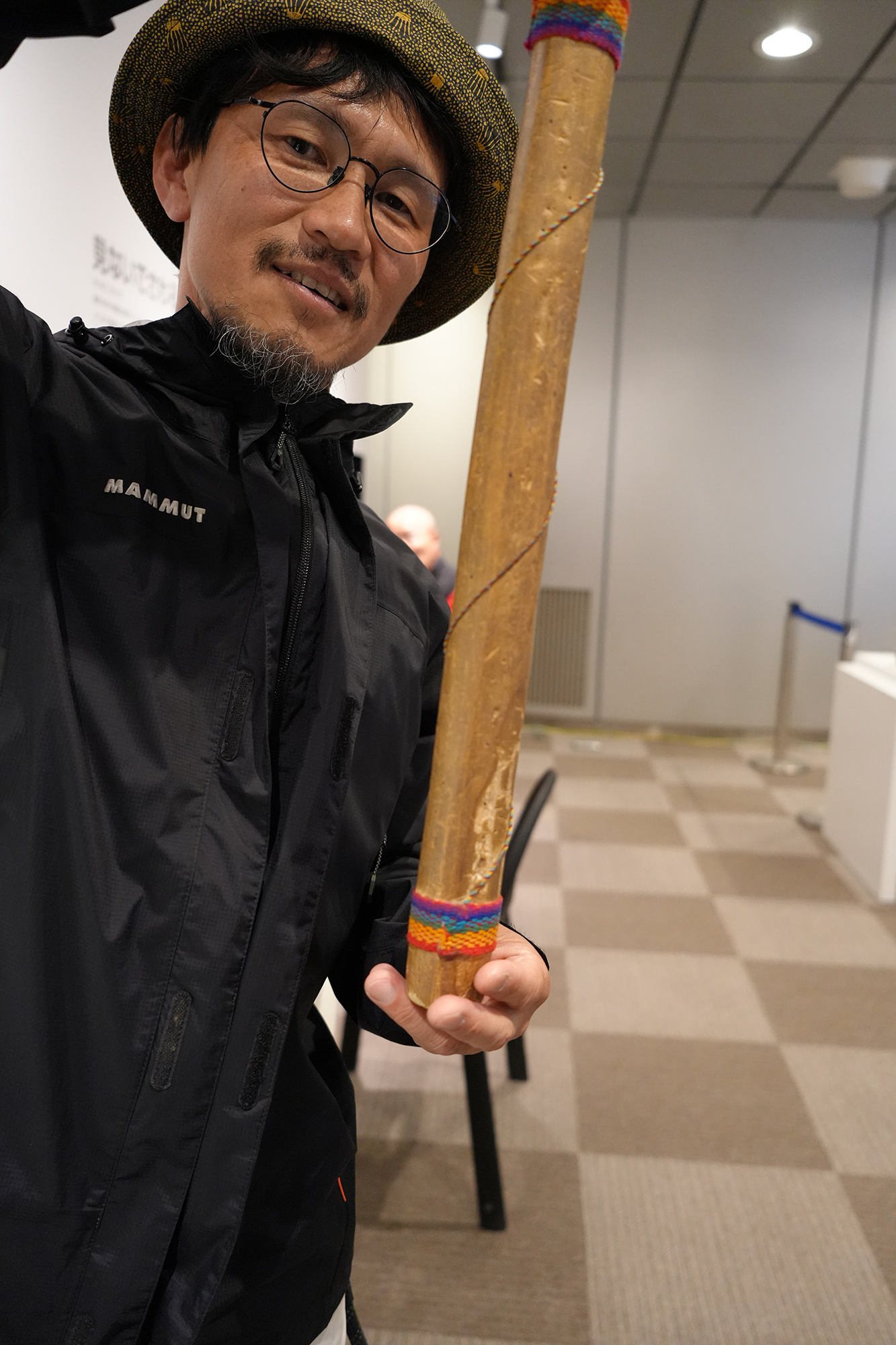 アマゾンの筒状の楽器を縦向きに持つ白井さん。上側の手は画面から少しはみ出している。