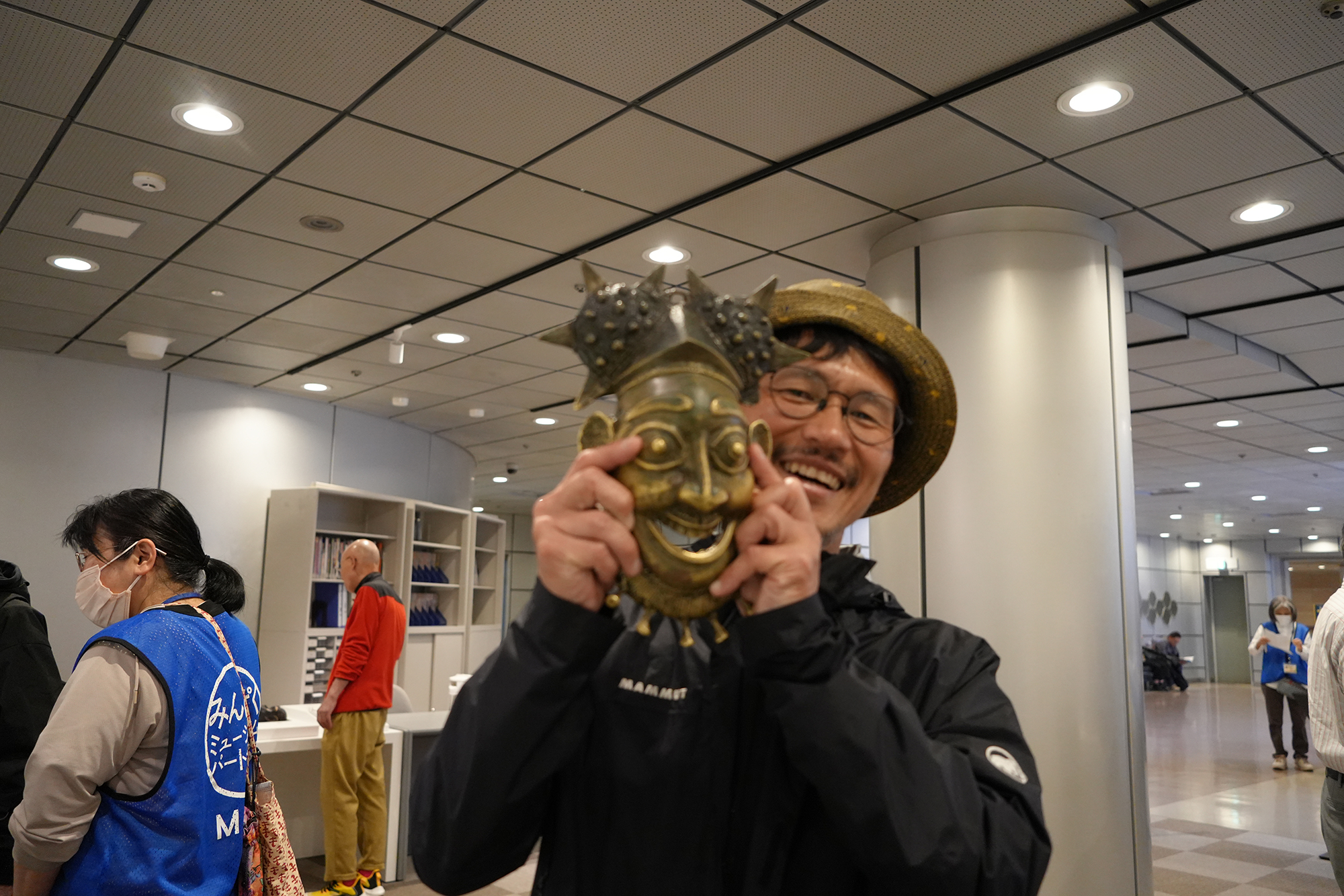 バムン族の王様の仮面を持ち、横から顔を覗かせる白井さんを撮影した写真。