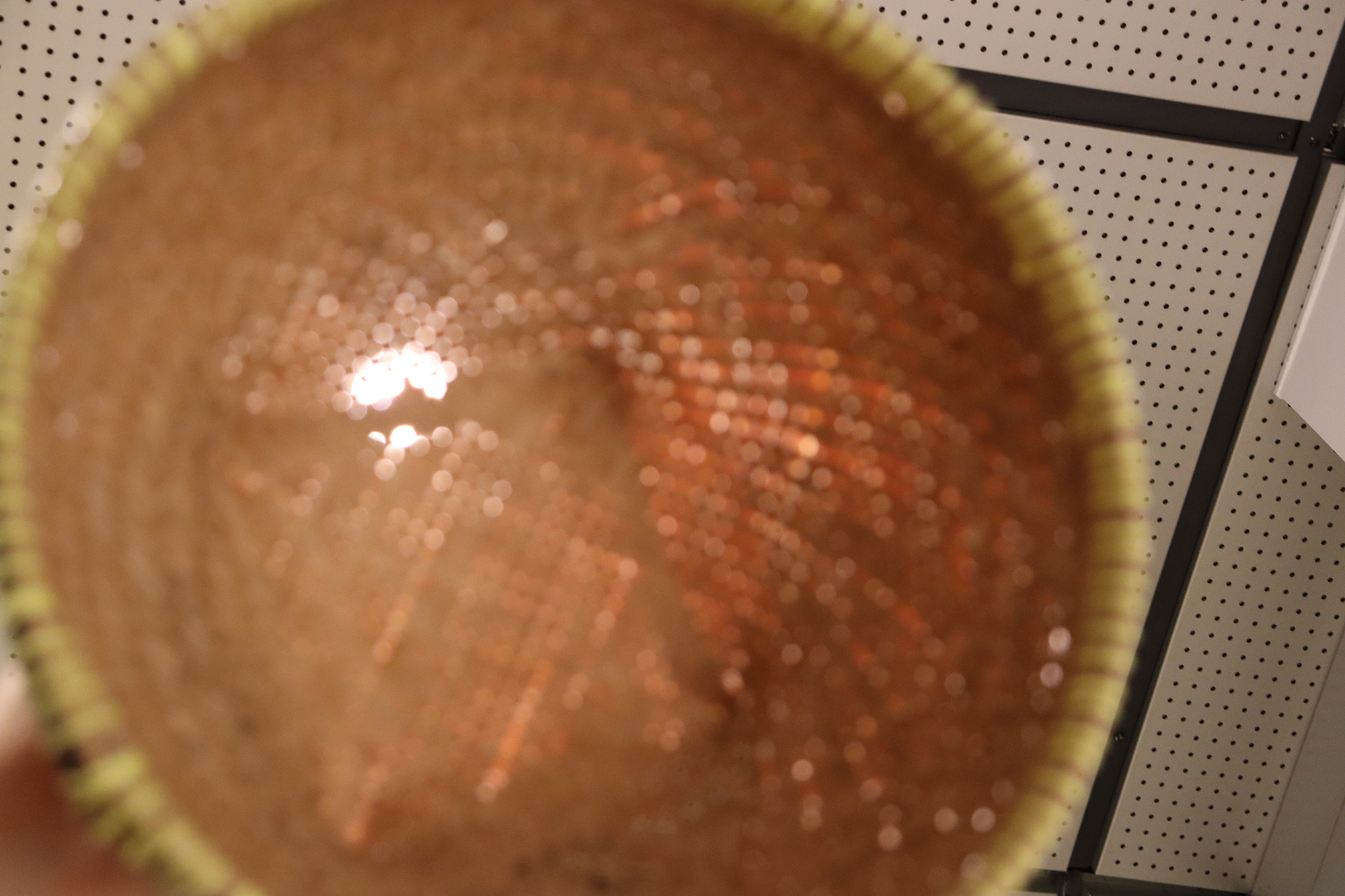 竹を細かく編んで作られた丸いご飯入れを真上から撮影した写真。中央付近はややぼけて見え、編み目が放射状に広がっている。